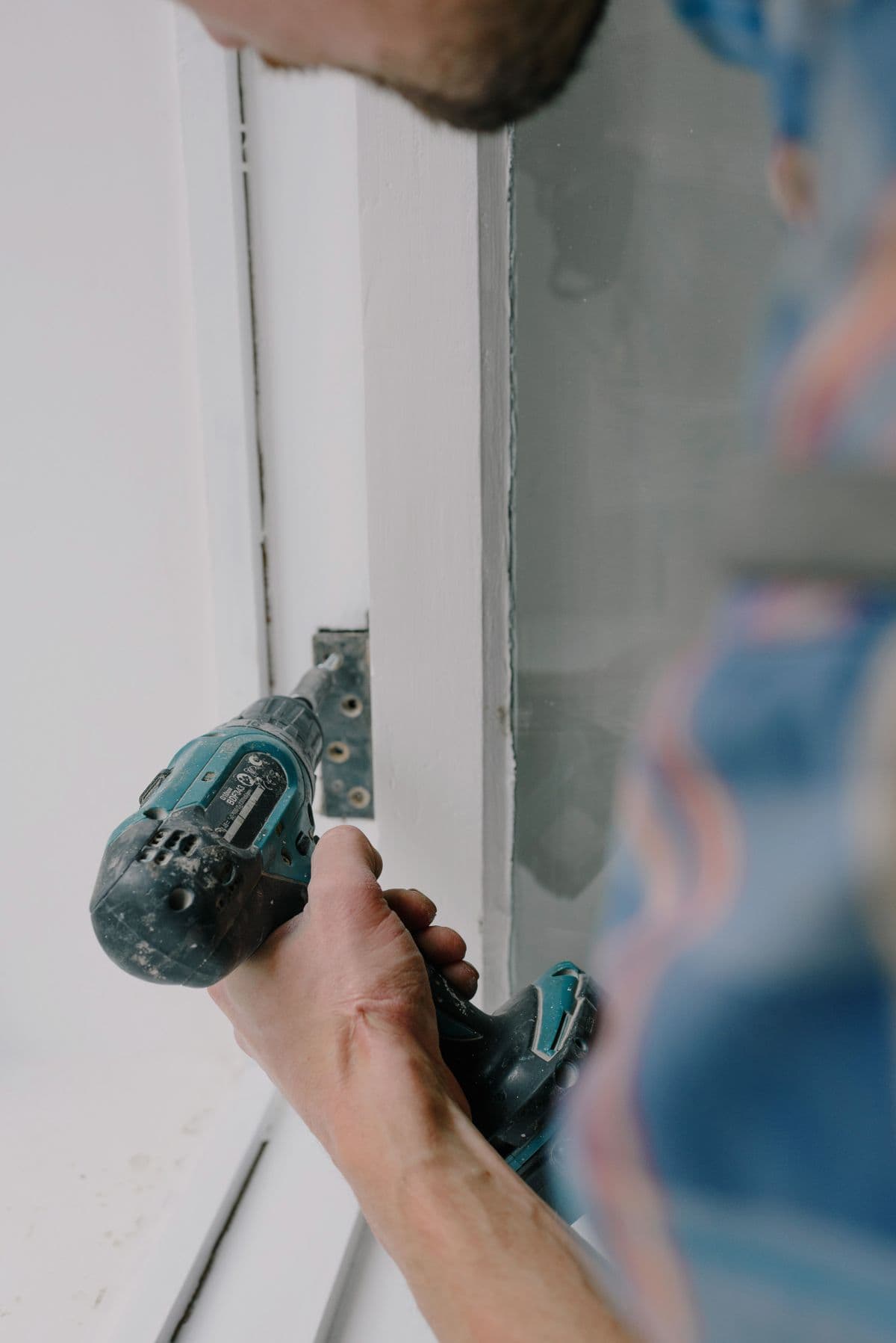 Mãos a fixar a dobradiça da porta de um armário durante uma obra.