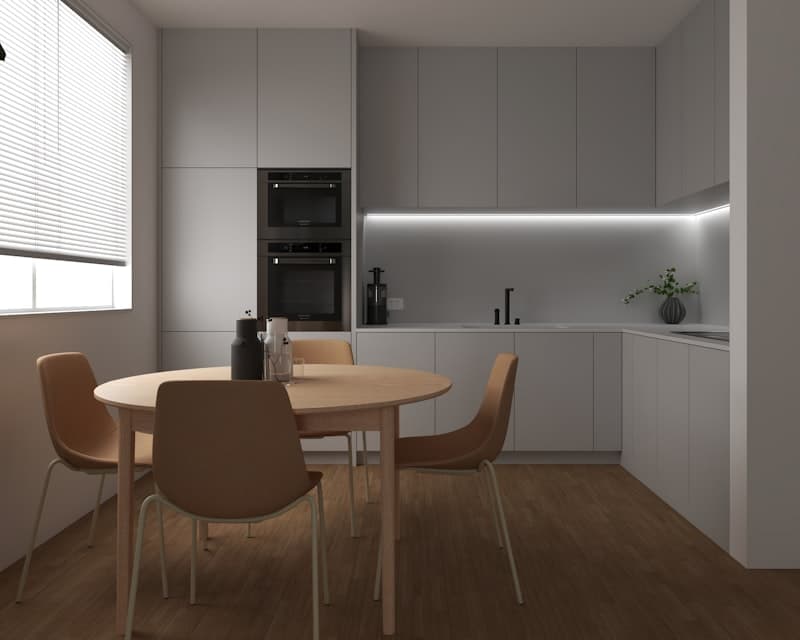 Une cuisine moderne aux meubles gris clair, avec une table ronde en bois et quatre chaises sur un parquet.